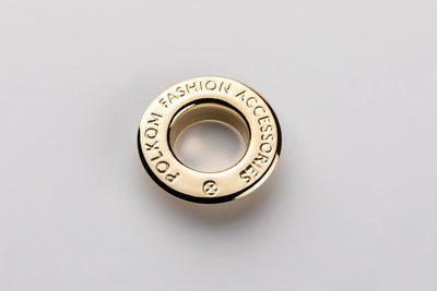 Œillet métallique avec nom de marque en relief sur la collerette, couleur or – exemple avec l'inscription Polkom
