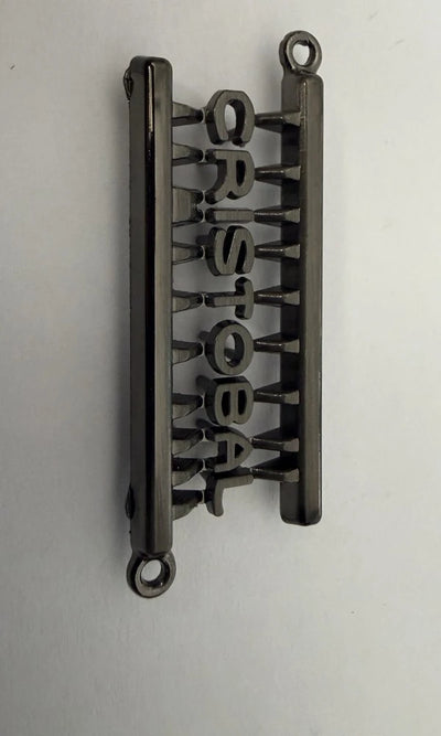 Gunmetal metal skriftlogo med prongs – på monteringsramme der knækkes af efter montering