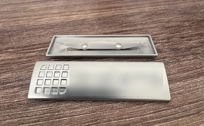 Metallskylt för laptopfodral i matt silver med präglad logotyp utan emalj och två ben baktill