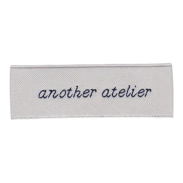 Lichtgrijs zacht geweven label met handgeschreven logo